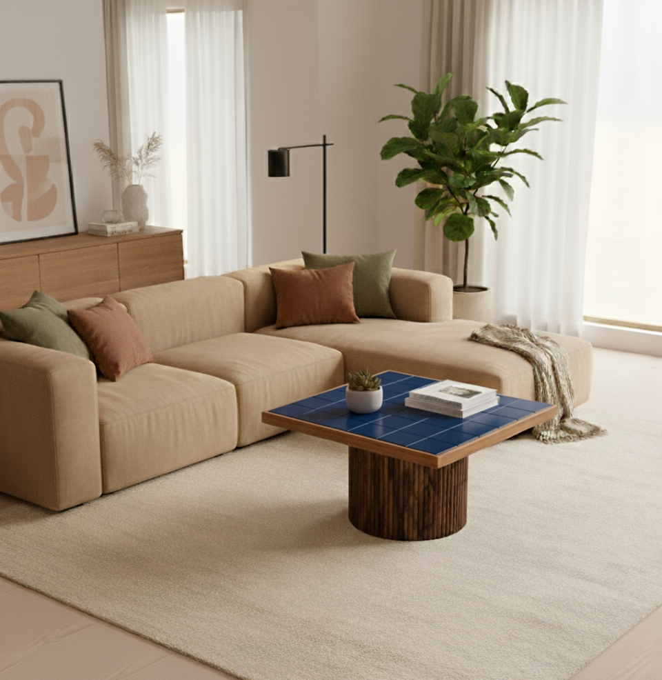 Modern living room with beige sectional sofa, blue coffee table, and decorative elements.